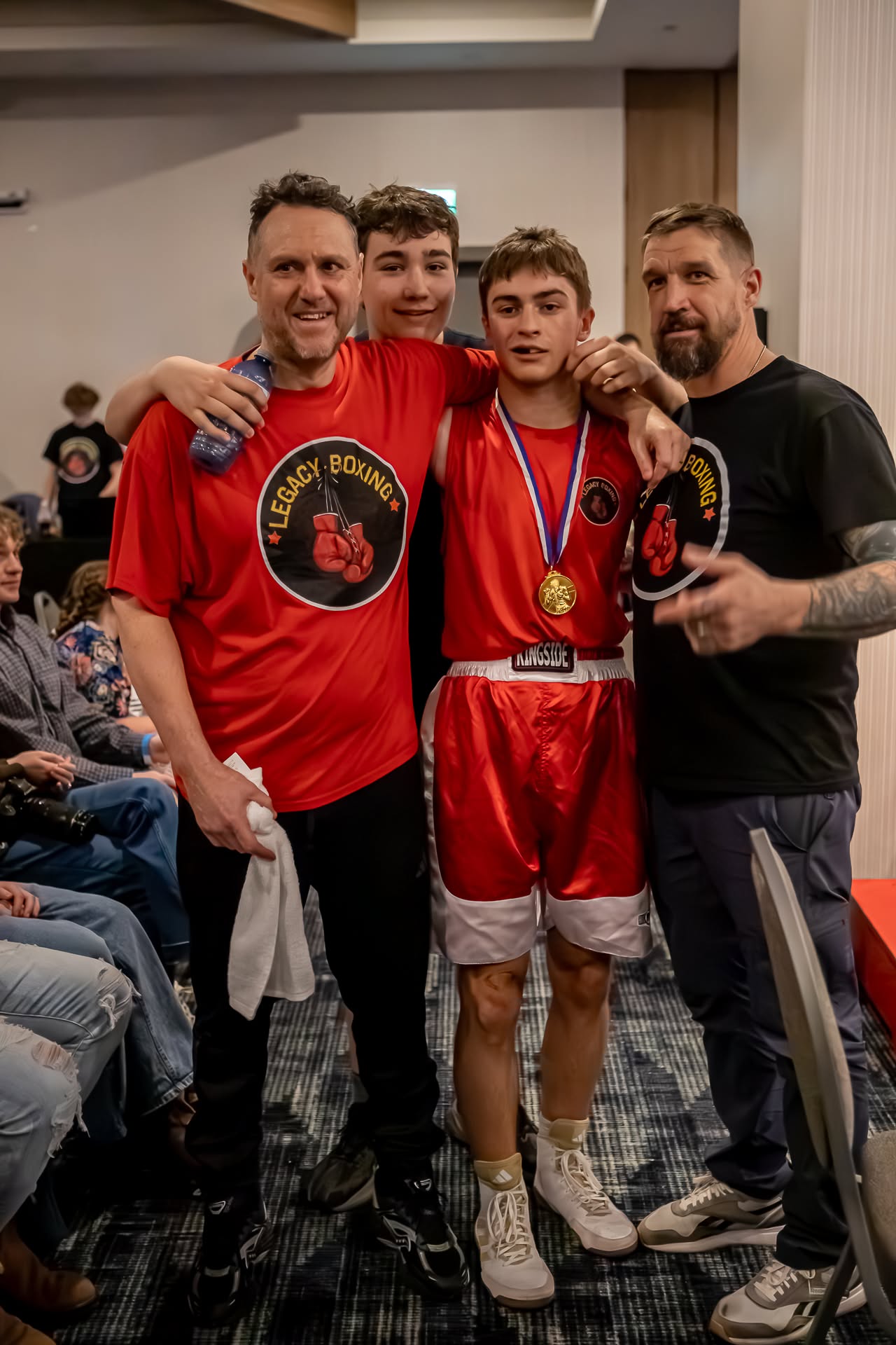 Legacy Boxing athlete with coaches after winning a medal
